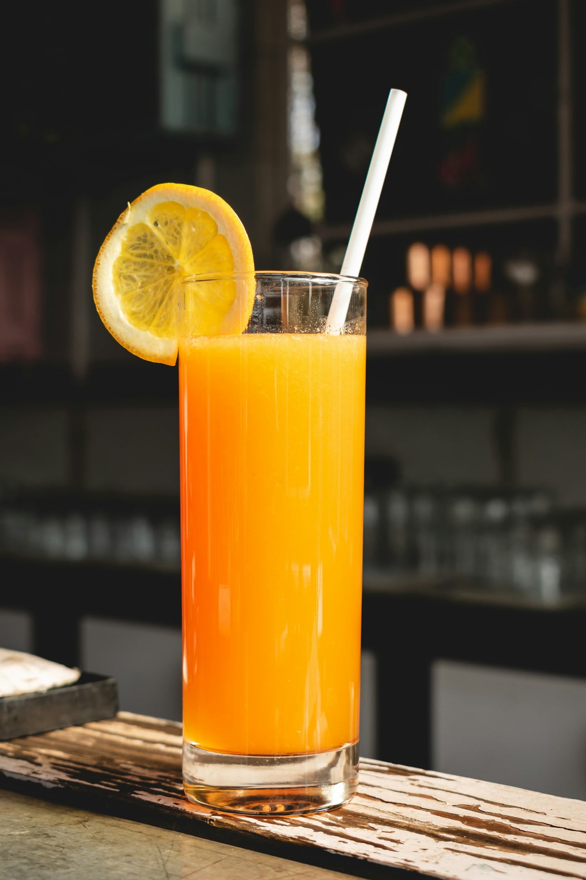 A glass of orange drink on a bright background, illustrating a light, juice-style clear whey protein drink