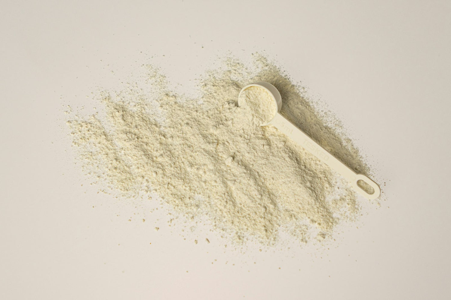 A measuring scoop of white creatine monohydrate powder on a clean white background