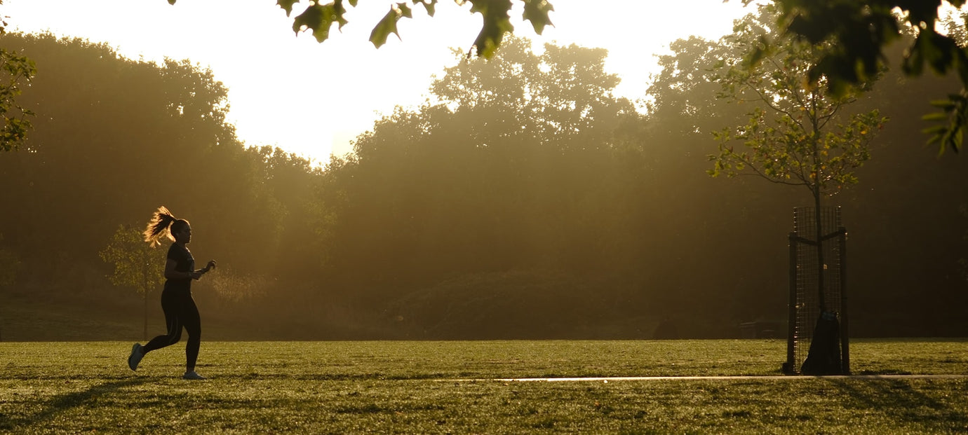 A runner training in a London park at sunrise on an autumn morning, illustrating low winter sunlight and vitamin D