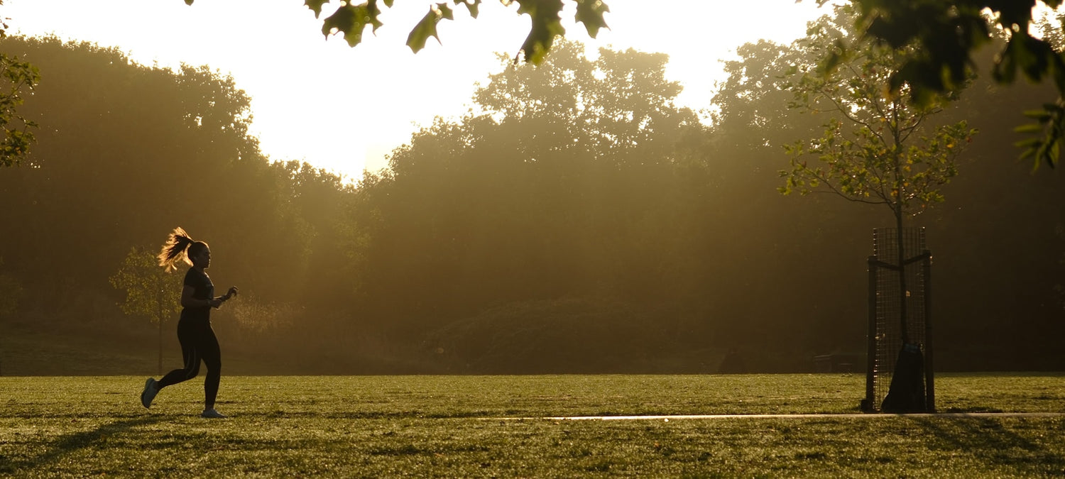 A runner training in a London park at sunrise on an autumn morning, illustrating low winter sunlight and vitamin D