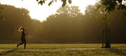A runner training in a London park at sunrise on an autumn morning, illustrating low winter sunlight and vitamin D